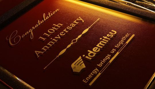 バカラのアビスフォトフレームに出光110周年記念として名入れ彫刻された写真。出光のロゴと“energy brings us together”のメッセージが美しく刻まれた、企業の節目を祝う高級感あふれる記念品