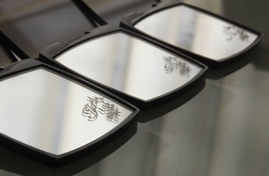 3つのシャネルのコンパクトミラーが並び、それぞれの下部ミラーに異なるデザインのイニシャルが名入れ彫刻された写真。フォントや装飾のバリエーションを一度に比較でき、個々のスタイルに合わせたカスタマイズの魅力を伝えるイメージ。