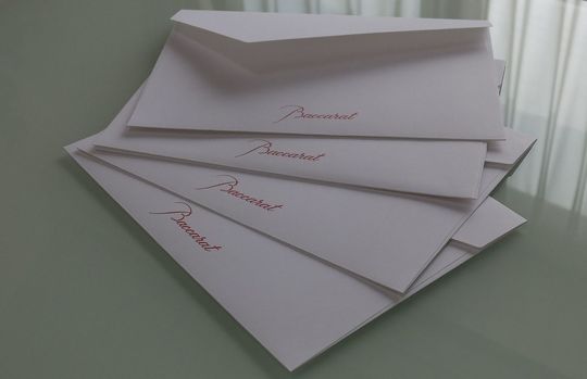 バカラの白い封筒に赤文字で「Baccarat」と印刷された高級感あるメッセージカードのクローズアップ写真 ギフトに添える上品なブランドカードの詳細イメージ