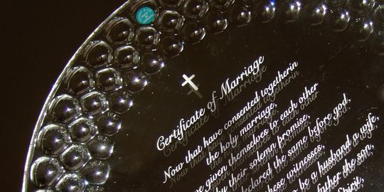 ティファニーのハチの巣の皿へ結婚証明書を名入れ彫刻した写真。繊細なハニカム模様が施されたティファニーの美しい皿に、お二人の永遠の愛を誓う結婚証明書の内容が丁寧に刻まれています。