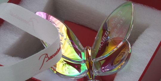 バカラのラッキーバタフライ、イリゼクリアの両羽根にホールインワンの記念を名入れ彫刻した写真。光の加減で虹色に輝く美しい蝶の羽根に、『〇〇ゴルフ場 No.〇〇 Date:〇〇〇〇 名前 Hole in One』と、輝かしい偉業を記念する文字が左右の羽根に繊細に刻まれています。