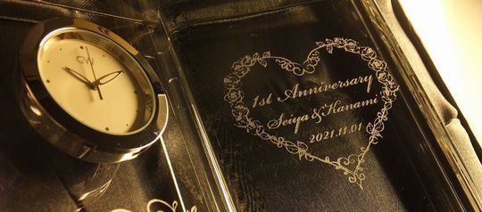 グラスワークスナルミのディクショナリークロックに、バラの花でハートを作ったデザインと共に「1st Anniversary」の文字、そしてお二人の名前と記念日が名入れ彫刻された特別な結婚記念ギフト。美しい彫刻が、1年目の結婚を祝う思い出を永遠に刻みます