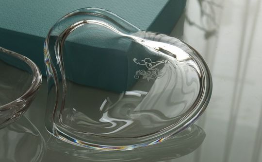 ティファニーのクリスタルハートボックスの上蓋に、イニシャルデザイン『A』を名入れ彫刻した写真。透明なクリスタルのハート型ボックスに、世界に一つだけのパーソナルなイニシャルが丁寧に刻まれています。誕生日や記念日、または特別な日の感謝を伝えるギフトに最適です。