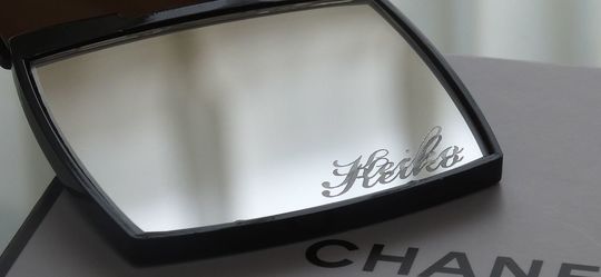 シャネルのミラー下部に、流麗なスクリプト体で『Keiko』と名入れ彫刻が施された写真。自分だけの特別感を演出する、繊細でエレガントなパーソナルギフトのイメージ。