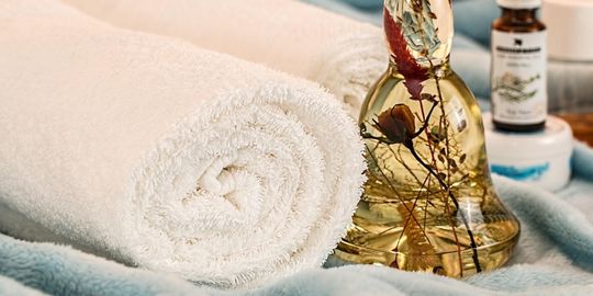 アロマセラピーとマッサージを行う前に、テーブルの上に置かれたエッセンシャルオイルとバスタオルの写真。