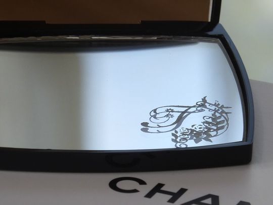 シャネルのコンパクトミラーに施されたイニシャル彫刻のクローズアップ｜上質なアイテムに特別な想いを込めるパーソナルギフト