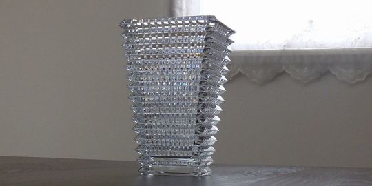 バカラのアイベース スクウェアがテーブルの上に置いてある写真。光の反射が美しいアイベースに、直線的なスクウェアのフォルムが組み合わされ、名入れギフトとしてのモダンで洗練された美しさと、空間に存在感を添える逸品です。