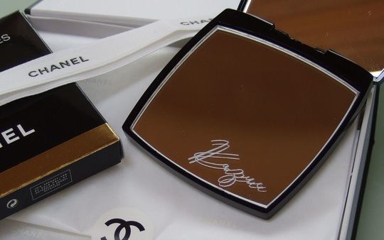 シャネルのコンパクトミラーの下のミラー右下に、スクリプト体で『Kazue』と名入れ彫刻を施した写真。洗練されたデザインにパーソナルなアクセントが加わり、特別な贈り物に最適なアイテムです。