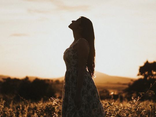 自然の中で空を見上げる一人の女性の写真。未来の自分へ気持ちを上げるアイテムとして、希望に満ちた表情と開放的な風景が、前向きな気持ちを後押しします。