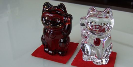 バカラの招き猫 レッドがテーブルの上に置いてある写真。情熱的な赤いクリスタル製の招き猫が、その美しいフォルムと光の反射で、空間に幸運と洗練された雰囲気をもたらしています。名入れギフトとしても、インテリアとしても魅力的な逸品です。