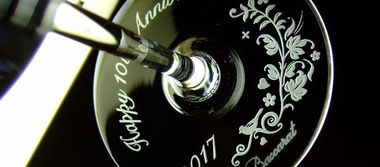 バカラのワイングラスの底面に「Happy 10th Anniversary」の文字と西暦、華やかな装飾デザインが名入れ彫刻された10周年記念の特別な贈り物。美しいデザインが10年の愛と絆を祝います