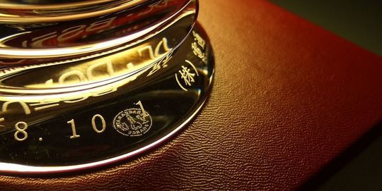 バカラのラランドクロックの背面下部に、アーチ状に配置された日付と企業名を名入れ彫刻したアップの写真。高度な技術と繊細な彫刻により、文字が優美な曲線を描き、クリスタルの輝きと相まって特別な存在感を放っています。