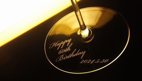 リーデル・ファット・ア・マーノシリーズのカベルネ/メルログラスに還暦祝いの名入れ彫刻を施した写真。特別な日のための贈り物として、エレガントなデザインとカスタマイズ可能な彫刻が魅力のワイングラス