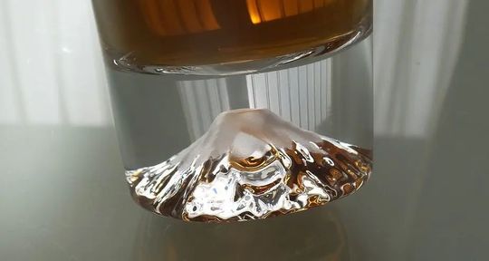 退職祝いにおすすめの名入れ富士山グラス。底面に彫刻された富士山が、注がれた飲み物の美しい色に染まり、特別な感謝のメッセージが輝く写真