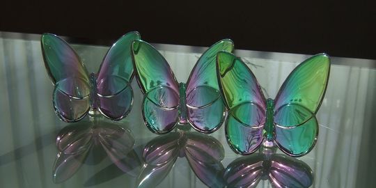 バカラオブジェの商品紹介写真：テーブルの上に横一列に並べられた、ラッキーバタフライ イリゼクリア3点。見る角度によって色が変わる幻想的な輝きと、バカラの繊細なクリスタル技術が際立つレイアウトです。