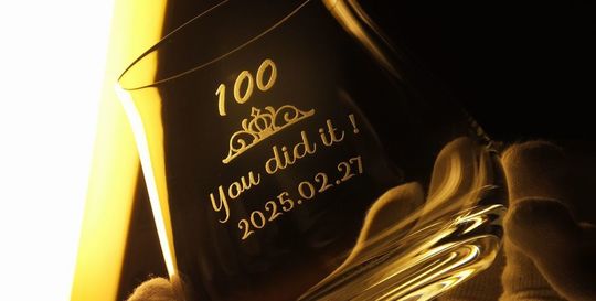 シャトーバカラタンブラーの側面に彫刻された100歳の誕生日を祝うメッセージとデザイン、記念日。高級クリスタルのタンブラーに華やかな装飾と共に、特別な100歳の誕生日を祝う思いを込めた名入れ彫刻が施され、贈り物としても大変価値のあるアイテム