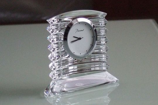 バカラのラランドクロックがエレガントにテーブルの上に置かれ、クリスタルの精緻なデザインが光を反射し、高級感と洗練された雰囲気を醸し出す