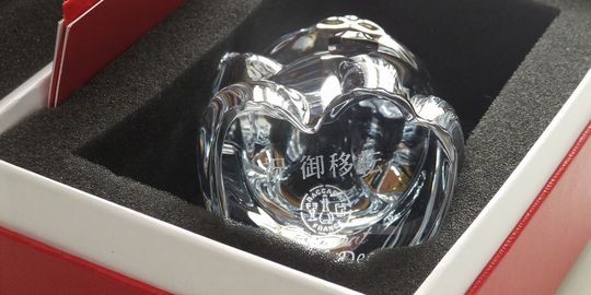 バカラの招き猫 レッドオクトゴンの底面に、『祝ご移転 お店の名前』を名入れ彫刻した写真。八角形の台座を持つ赤い招き猫の底に、新たな門出を祝うメッセージが繊細に刻まれています。商売繁盛と移転を祝う特別な贈り物として洗練された逸品です。