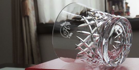 バカラのアリアタンブラーの側面に、イニシャルデザイン『K』を名入れ彫刻した写真。透明なクリスタル製のタンブラーに、贈り主のイニシャルがエレガントに刻まれています。パーソナルな想いを伝える、特別な記念品やギフトにふさわしい逸品です。