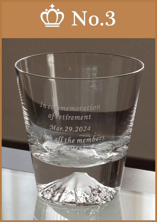 田島硝子の富士山ロックグラスの側面に、退職祝いのメッセージや日付、名前を名入れ彫刻した写真。グラスの底に浮かび上がる精巧な富士山と、側面に刻まれたこれまでの功績を称える刻印が調和した、門出を祝う特別な贈り物としてのディテール。
