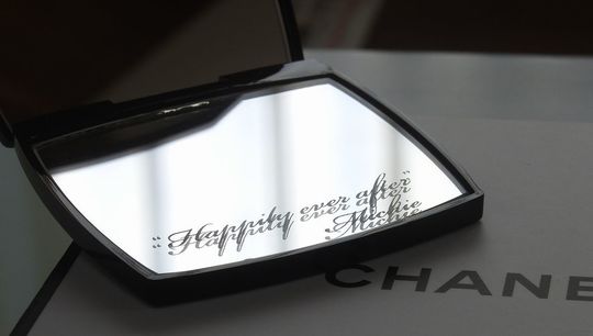 シャネルのコンパクトミラーに「Happily ever after」のメッセージと名前が彫刻された、特別感あふれる名入れギフトの写真。結婚祝いや記念日の贈り物に最適です。